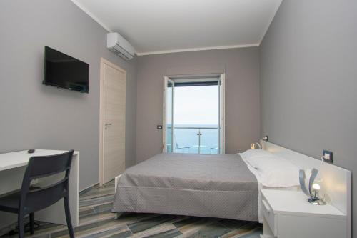 Schlafzimmer mit einem Bett, einem Schreibtisch und einem Fenster in der Unterkunft La Dimora sul Mare in Marina di Camerota