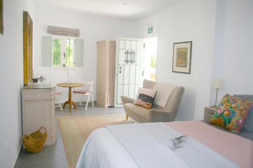 a bedroom with a bed and a chair and a table at La Pluma in Iznájar