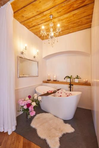 a bath tub in a bathroom with a chandelier and flowers at Przystanek Szlakówka in Szczebrzeszyn