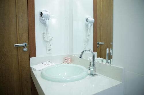 a bathroom with a white sink and a phone at Hotel Uipi in Sorriso