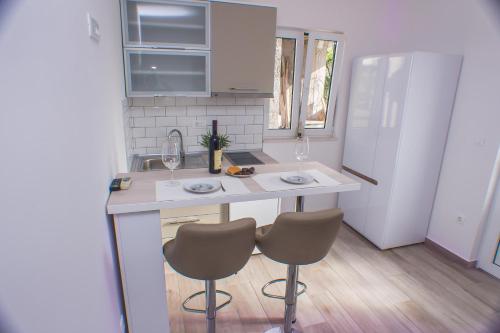 a kitchen with two chairs and a counter with wine glasses at DMM Apartments in Tivat