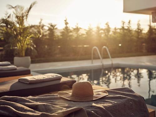 a hat sitting on a table next to a swimming pool at Errikos Family Villa - Serene Environment and Private Pool, by ZanteWize in Ayios Kirikos
