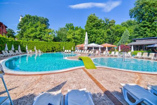 a pool with chairs and umbrellas in a resort at Семеен хотел Анна-Кристина in Vidin
