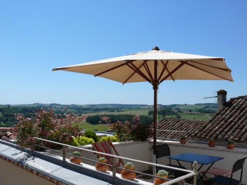 a balcony with a table and an umbrella at Hôtel Étoiles d'Orion in Marsolan