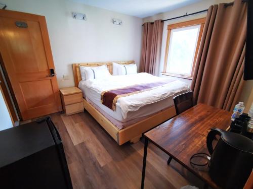 a bedroom with a bed and a table and a window at Riverfront Estate Bed&Breakfast Banff in Banff
