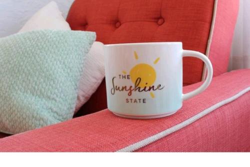 a coffee cup sitting on top of a bed at Lake Worth Beach Paradise Cove Cottage 2-1Bedroom in Lake Worth