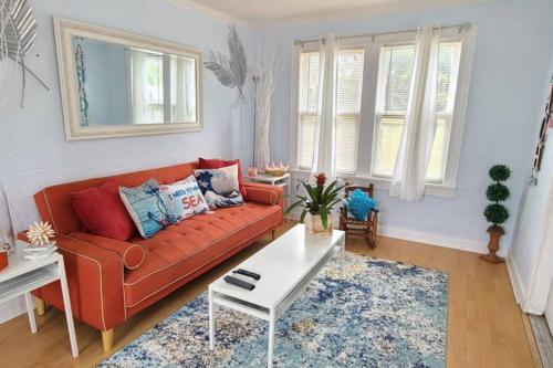 a living room with a red couch and a white table at Lake Worth Beach Paradise Cove Cottage 2-1Bedroom in Lake Worth
