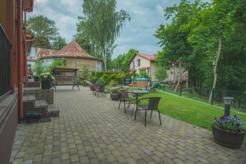 a patio with tables and chairs in a yard at Senasis Nemunas in Druskininkai