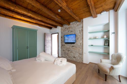 a bedroom with a bed and a chair and a tv at Casa Castagna 1620 in Mergozzo