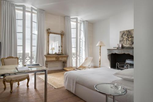 um quarto com uma cama, uma mesa e um espelho em L'Hôtel Particulier em Arles
