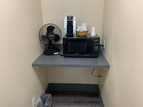 a kitchen counter with a microwave and a cupboard at Coastal Inn and Suites in Long Beach
