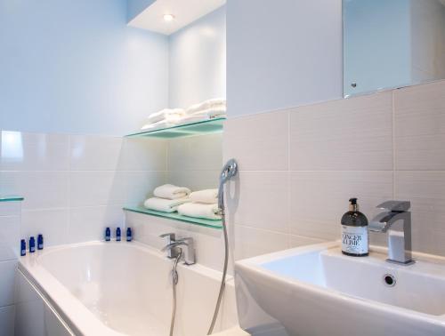 a white bathroom with a tub and a sink at The Courtyard Lymm in Lymm