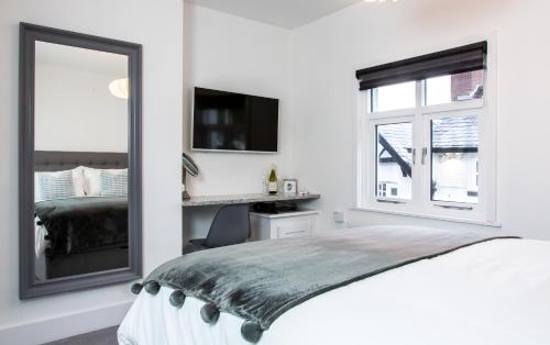 um quarto branco com uma cama e um espelho em The Courtyard Lymm em Lymm