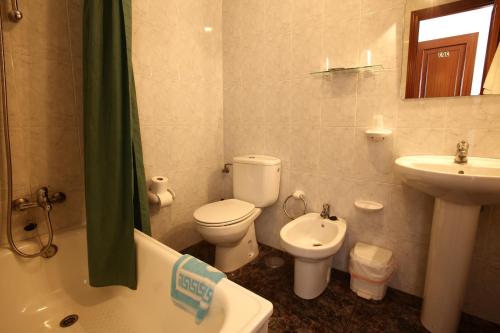 a bathroom with a toilet and a sink and a tub at Hostal San Roque in Portonovo