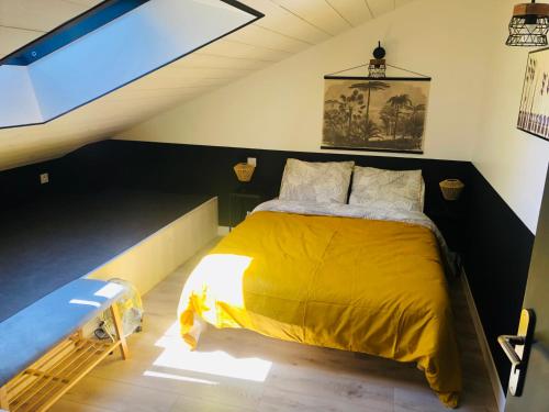 ein Schlafzimmer mit einem gelben Bett im Dachgeschoss in der Unterkunft Le Ristouar Spa forêt et mer in Quimperlé