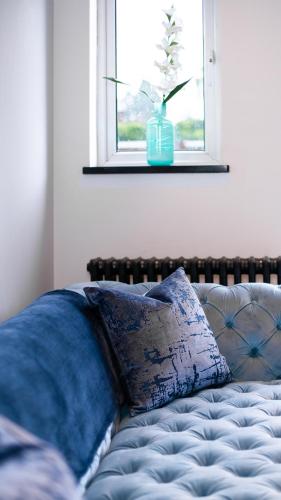 a bed with a pillow and a window with a vase at The Courtyard Lymm in Lymm