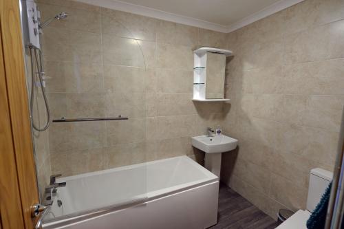 a bathroom with a bath tub and a sink at Mermaid Apartment - Sea Front Apartment with Views in Saundersfoot