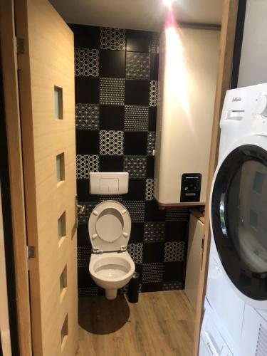 a bathroom with a toilet with a black and white wall at Le Ristouar Spa forêt et mer in Quimperlé