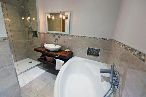 a bathroom with a bath tub and a sink at Priory Cottage - Luxury Cottage, Near to Beach in Saundersfoot