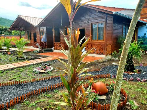 a wooden house with a palm tree in front of it at CASA BLANCA HORTENCIA in Sucúa