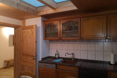 cocina con armarios de madera, fregadero y encimera en Andermichlhof (3)Ferienwohnung Groß Landsberger Strasse 8, en Geltendorf