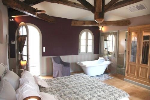 a bedroom with a large bed and a bath tub at Hôtel Étoiles d'Orion in Marsolan