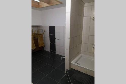 a bathroom with a tub and white tiles at Andermichlhof (3)Ferienwohnung Groß Landsberger Strasse 8 in Geltendorf