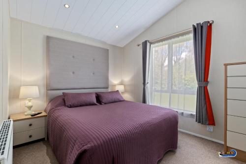 a bedroom with a purple bed and a window at St Mary's View - Luxury Lodge, Short Walk to Beach, Parking in Tenby