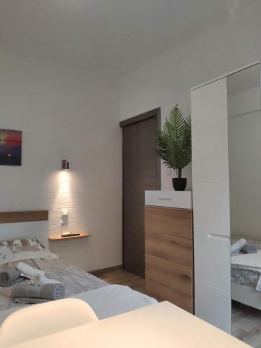 a bedroom with a bed and a plant on a dresser at Comfort Apartment by Prima Lodging in Thessaloniki