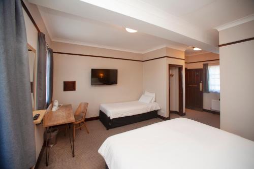 a hotel room with a bed and a desk and a bed at Shah of Persia, Poole by Marston's Inns in Poole