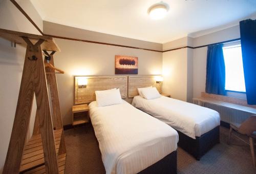 a hotel room with two beds and a window at Shah of Persia, Poole by Marston's Inns in Poole