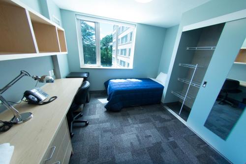 オリリアにあるLakehead University Residence and Conference Centreのベッド、デスク、窓が備わる客室です。