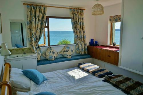 ein Schlafzimmer mit einem Bett mit Blick auf das Meer in der Unterkunft The Cottage - Sea Views, Direct Access to Beach, Pet Friendly in Stepaside