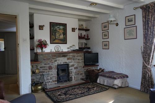 ein Wohnzimmer mit Kamin und Fernseher in der Unterkunft The Cottage - Sea Views, Direct Access to Beach, Pet Friendly in Stepaside