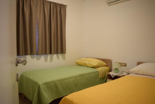 Cette chambre comprend 2 lits et une fenêtre. dans l'établissement Apartmani Jelenić, à Ždrelac