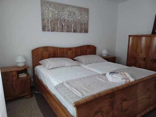 a bedroom with a bed with a wooden frame and a painting at Walk Apartment in Vukovar