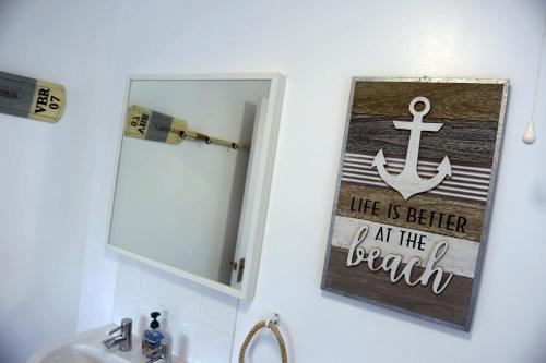 a bathroom mirror with a sign that reads life is better at the beach at Valley Retreat - Peaceful Location, Walk to Beach, Parking in Saundersfoot