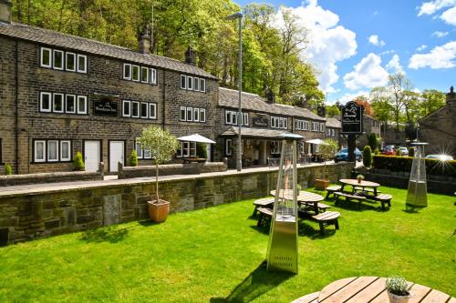 a building with a green yard with tables and benches at The Woodman Inn in Huddersfield
