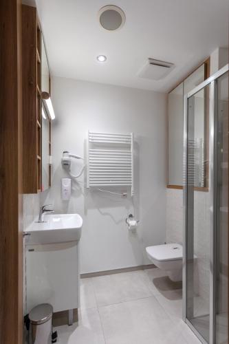 a white bathroom with a sink and a toilet at Wolska Residence I in Warsaw
