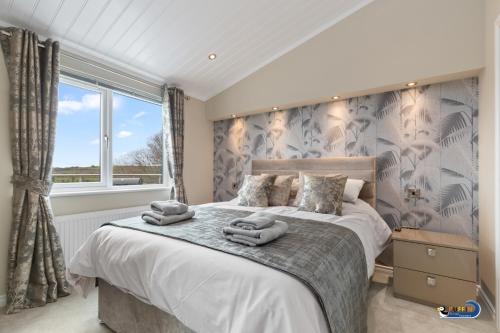 a bedroom with a large bed with towels on it at Valley View Lodge - Luxury Lodge, Hot Tub, Close to Beach in Penally