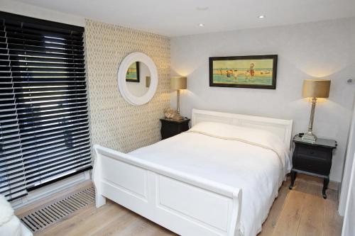 a bedroom with a white bed and a mirror at Aan Zee en Duin in Egmond aan Zee