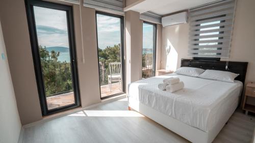 een slaapkamer met een wit bed en grote ramen bij Camlik Deniz Yildizi Hotel in Ayvalık