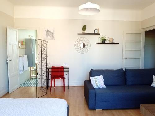 uma sala de estar com um sofá azul e uma mesa vermelha em Les Cocons de Stéphanie avec balcon em Vichy
