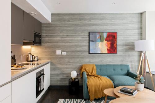 a living room with a blue couch and a kitchen at COVE Cannon Street in London