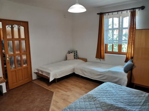a bedroom with two beds and a window at Éva Apartmanház 2 in Csopak