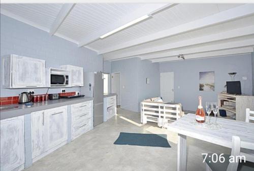 a large kitchen with white cabinets and a table at Cottage on Atlantic90 in Yzerfontein