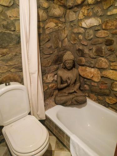 a bathroom with a statue of a buddha sitting on a bath tub at El Molino de la Ropería in Serrilla