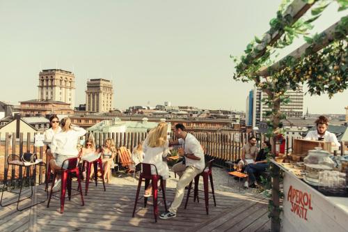 a group of people sitting on bar stools on a rooftop at Hotel With Urban Deli in Stockholm