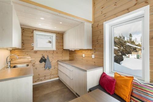 una pequeña cocina con fregadero y ventana en Tiny mountain cabin with a panoramic view, en Giljane