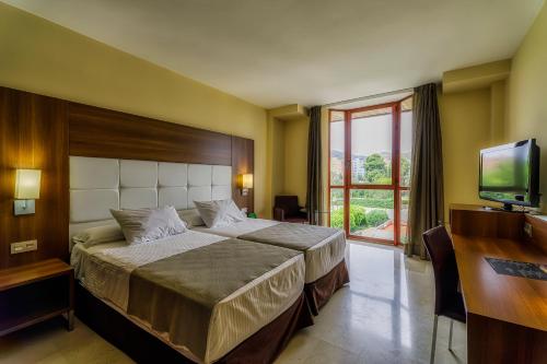 Spa Jardines de Lorca في لوركا: غرفة نوم بسرير ومكتب وتلفزيون